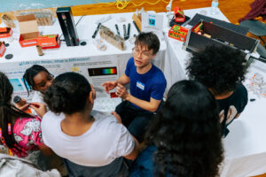 SPARK 2024. Alex Deters, Michal Szurek, and Annie Zhi from the Greiner group walk students through making holograms and spectroscopes.