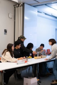 Some students explore resonances with tuning forks while other students attempt to place electrodes into a model of a vacuum chamber.
